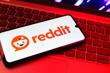 Prag, Çek Cumhuriyeti - 08 01 2025: Dizüstü bilgisayarın üzerinde duran bir cep telefonu Reddit logosunu gösterir. Reddit tartışma, haber ve toplum içeriği için bir platformdur.