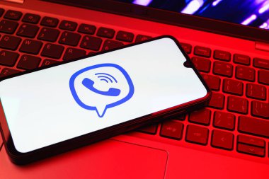 Prag, Çek Cumhuriyeti - 08 01 2025: Dizüstü bilgisayarın üzerinde duran bir cep telefonu Viber logosunu gösteriyor. Viber aramalar, mesajlar ve medya paylaşımı için bir mesajlaşma uygulamasıdır.