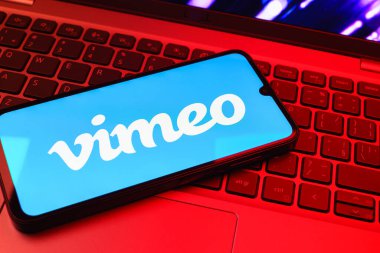 Prag, Çek Cumhuriyeti - 08 01 2025: Dizüstü bilgisayarın üzerinde duran bir cep telefonu Vimeo logosunu gösterir. Vimeo, yüksek kaliteli video sunucu ve paylaşımı için bir platformdur.