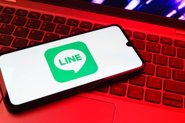 Prag, Çek Cumhuriyeti - 08 01 2025: Dizüstü bilgisayarın üzerinde duran bir cep telefonu Hat logosunu gösterir. Line aramalar, mesajlar ve çokluortam paylaşımı için bir mesajlaşma uygulamasıdır.