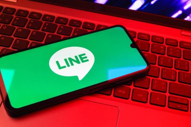 Prag, Çek Cumhuriyeti - 08 01 2025: Dizüstü bilgisayarın üzerinde duran bir cep telefonu Hat logosunu gösterir. Line aramalar, mesajlar ve çokluortam paylaşımı için bir mesajlaşma uygulamasıdır.