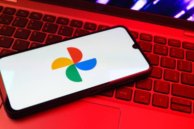 Prag, Çek Cumhuriyeti - 08 01 2025: Laptop klavyesinde duran bir cep telefonu Google Photos logosunu görüntüler. Google Fotoğrafları fotoğraf ve videoları saklamak ve düzenlemek için bir platformdur.