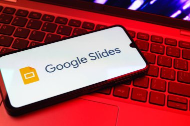 Prag, Çek Cumhuriyeti - 08 01 2025: Laptop klavyesinde duran bir cep telefonu Google Slides logosunu görüntüler. Google Slides sunumlar ve slayt gösterileri oluşturmak için bir platformdur.