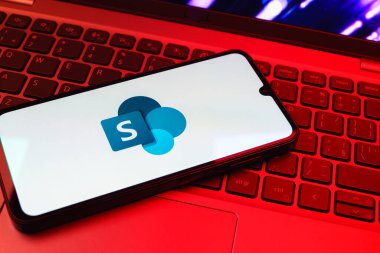 Prag, Çek Cumhuriyeti - 08 01 2025: Dizüstü bilgisayarın üzerinde duran bir cep telefonu Microsoft Sharepoint logosunu gösteriyor. Microsoft Sharepoint işbirliği ve belge yönetimi için bir platformdur.