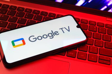 Prag, Çek Cumhuriyeti - 08 01 2025: Laptop klavyesinde uzanan bir cep telefonu Google TV logosunu gösteriyor. Google TV film, program ve uygulamalar için bir platformdur..