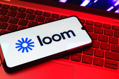 Prag, Çek Cumhuriyeti - 08 01 2025: Laptop klavyesinde duran bir cep telefonu Loom logosunu gösterir. Loom video mesajlarını kaydetmek ve paylaşmak için bir platformdur.