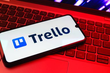Prag, Çek Cumhuriyeti - 08 01 2025: Dizüstü bilgisayarın üzerinde duran bir cep telefonu Trello logosunu gösterir. Trello, tahta ve görevleri kullanarak proje yönetimi için bir platformdur.