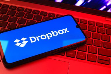 Prag, Çek Cumhuriyeti - 08 01 2025: Laptop klavyesinde duran bir cep telefonu Dropbox logosunu gösterir. Dropbox bulut depolama ve dosya paylaşımı için bir platformdur.
