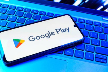 Prag, Çek Cumhuriyeti - 08 01 2025: Dizüstü bilgisayarda bulunan bir cep telefonu Google Play logosunu görüntüler. Google Play uygulamaları, oyunları ve dijital içeriği indirmek için bir platformdur.