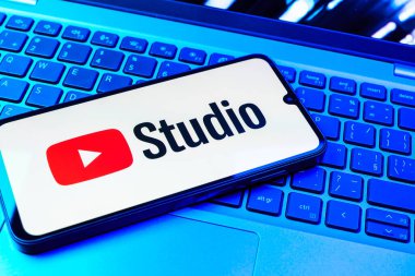 Prag, Çek Cumhuriyeti - 08 01 2025: Laptop klavyesinde duran bir cep telefonu Youtube Stüdyo logosunu görüntüler. Youtube Studio YouTube kanallarını yönetmek ve analiz etmek için bir platformdur.