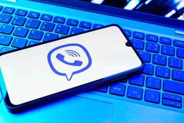 Prag, Çek Cumhuriyeti - 08 01 2025: Dizüstü bilgisayarın üzerinde duran bir cep telefonu Viber logosunu gösteriyor. Viber aramalar, mesajlar ve medya paylaşımı için bir mesajlaşma uygulamasıdır.