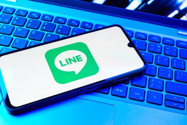 Prag, Çek Cumhuriyeti - 08 01 2025: Dizüstü bilgisayarın üzerinde duran bir cep telefonu Hat logosunu gösterir. Line aramalar, mesajlar ve çokluortam paylaşımı için bir mesajlaşma uygulamasıdır.