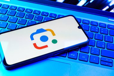 Prag, Çek Cumhuriyeti - 08 01 2025: Bir klavyenin üzerinde duran bir cep telefonu Google Lens logosunu görüntüler. Google Lens, resimlerdeki görsel arama ve bilgi için kullanılan bir araçtır..