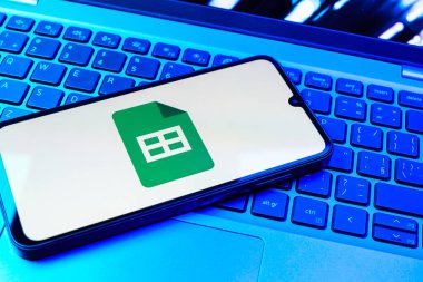 Prag, Çek Cumhuriyeti - 08 01 2025: Laptop klavyesinde duran bir cep telefonu Google Sheets logosunu görüntüler. Google Sayfalar tablo oluşturmak ve yönetmek için bir platformdur.