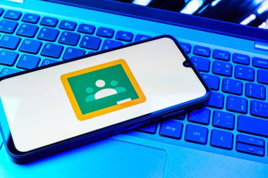 Prag, Çek Cumhuriyeti - 08 01 2025: Dizüstü bilgisayarda bulunan bir cep telefonu Google Sınıfı logosunu görüntüler. Google Sınıfı, sınıfları ve eğitim içeriğini yönetmek için bir platformdur.