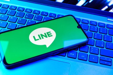 Prag, Çek Cumhuriyeti - 08 01 2025: Dizüstü bilgisayarın üzerinde duran bir cep telefonu Hat logosunu gösterir. Line aramalar, mesajlar ve çokluortam paylaşımı için bir mesajlaşma uygulamasıdır.