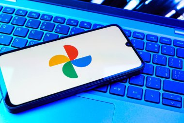 Prag, Çek Cumhuriyeti - 08 01 2025: Laptop klavyesinde duran bir cep telefonu Google Photos logosunu görüntüler. Google Fotoğrafları fotoğraf ve videoları saklamak ve düzenlemek için bir platformdur.