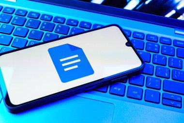 Prag, Çek Cumhuriyeti - 08 01 2025: Dizüstü bilgisayarda bulunan bir cep telefonu Google Docs logosunu görüntüler. Google Docs metin belgeleri oluşturmak ve düzenlemek için bir platformdur.