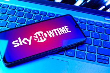 Prag, Çek Cumhuriyeti - 08 01 2025: Dizüstü bilgisayarın üzerinde duran bir cep telefonu SkyShowtime logosunu gösteriyor. SkyShowtime, sinema ve televizyon dizileri için bir yayın platformudur..