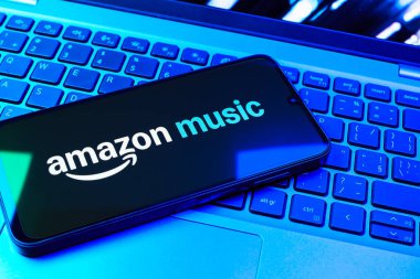 Prag, Çek Cumhuriyeti - 08 01 2025: Laptop klavyesinde uzanan bir cep telefonu Amazon Müzik logosunu gösteriyor. Amazon Müzik müzik müzik için bir platformdur..