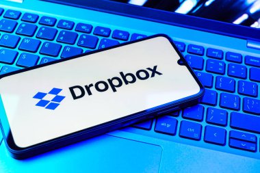 Prag, Çek Cumhuriyeti - 08 01 2025: Laptop klavyesinde duran bir cep telefonu Dropbox logosunu gösterir. Dropbox bulut depolama ve dosya paylaşımı için bir platformdur.