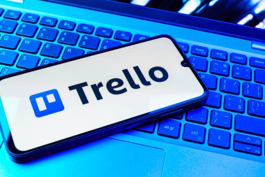 Prag, Çek Cumhuriyeti - 08 01 2025: Dizüstü bilgisayarın üzerinde duran bir cep telefonu Trello logosunu gösterir. Trello, tahta ve görevleri kullanarak proje yönetimi için bir platformdur.
