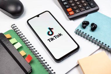 Prag, Çek Cumhuriyeti - 08 18 2025: Merkezde TikTok logosunu gösteren bir cep telefonu ile ofis malzemeleri düzenlemesi. TikTok kısa, yaratıcı ve viral video platformu.
