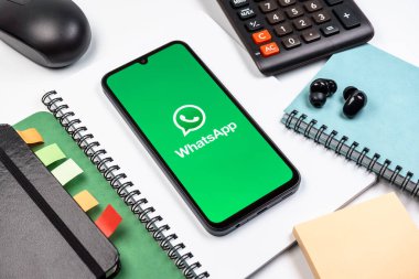 Prag, Çek Cumhuriyeti - 08 18 2025: Ofis malzemelerinin merkezde WhatsApp logosunu gösteren bir cep telefonu ile düzenlenmesi. WhatsApp mesaj, çağrı ve medya göndermek için bir uygulamadır.