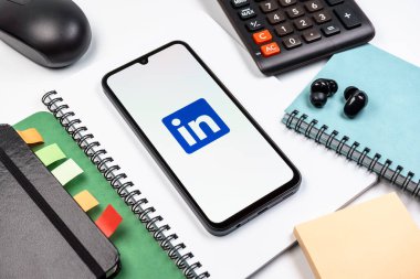 Prag, Çek Cumhuriyeti - 08 18 2025: Merkezde LinkedIn logosunu gösteren bir cep telefonu ile ofis malzemeleri düzenlemesi. LinkedIn, insanları ve şirketleri birbirine bağlayan profesyonel bir ağ..
