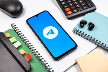 Prag, Çek Cumhuriyeti - 08 18 2025: Merkezde Telegram logosunu gösteren bir cep telefonu ile ofis malzemeleri düzenlemesi. Telgraf hızlı ve güvenli iletiler için bir uygulamadır.