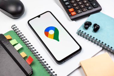 Prag, Çek Cumhuriyeti - 08 18 2025: Merkezde Google Maps logosunu gösteren bir cep telefonu ile ofis malzemeleri düzenlemesi. Google Maps haritalar, navigasyon ve konum hizmetleri için bir platformdur.