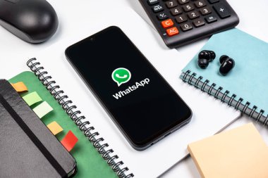Prag, Çek Cumhuriyeti - 08 18 2025: Ofis malzemelerinin merkezde WhatsApp logosunu gösteren bir cep telefonu ile düzenlenmesi. WhatsApp mesaj, çağrı ve medya göndermek için bir uygulamadır.