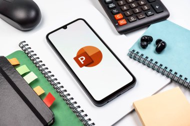 Prag, Çek Cumhuriyeti - 08 18 2025: Merkezde Powerpoint logosunu gösteren bir cep telefonu ile ofis malzemeleri düzenlemesi. Powerpoint sunumlar ve slayt gösterileri oluşturmak için bir yazılımdır..