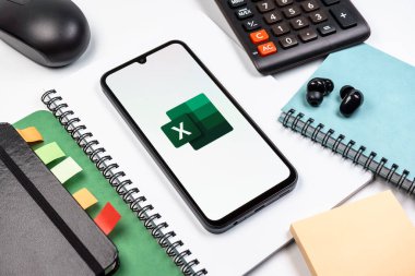 Prag, Çek Cumhuriyeti - 08 18 2025: Excel logosu sergilenen bir cep telefonu ile ofis malzemeleri düzenlemesi. Excel, tablo, veri analizi ve hesaplamalar için bir yazılımdır..