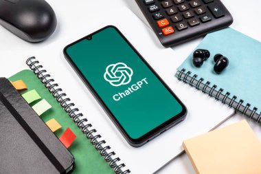 Prag, Çek Cumhuriyeti - 08 18 2025: Merkezinde ChatGPT logosu bulunan bir cep telefonu ile ofis malzemeleri düzenlemesi. ChatGPT metin üretmek ve soruları cevaplamak için bir yapay zeka sohbet robotudur..