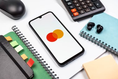 Prag, Çek Cumhuriyeti - 08 18 2025: Merkezde Mastercard logosu sergilenen bir cep telefonu ile ofis malzemeleri düzenlemesi. Mastercard ödeme kartları ve hizmetler sağlayan bir finans şirketidir..