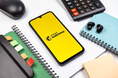 Prag, Çek Cumhuriyeti - 08 18 2025: Posta şempanzesinin logosunu gösteren bir cep telefonu ile ofis malzemeleri düzenlemesi. Posta şempanzesi e-posta pazarlama ve otomasyon için bir platformdur.