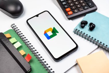Prag, Çek Cumhuriyeti - 08 18 2025: Merkezde Google Meet logosunu gösteren bir cep telefonu ile ofis malzemeleri düzenlemesi. Google Meet video toplantıları ve çevrimiçi işbirliği için bir platformdur.