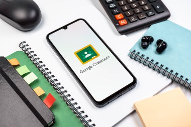 Prag, Çek Cumhuriyeti - 08 18 2025: Merkezde Google Sınıfı logosunu gösteren bir cep telefonu ile ofis malzemeleri düzenlemesi. Google Sınıfı, sınıfları ve eğitim içeriğini yönetmek için bir platformdur.