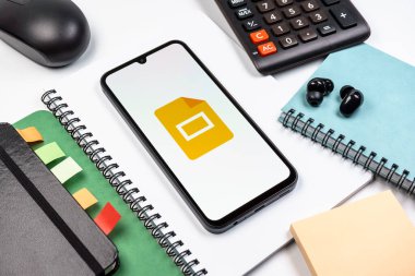 Prag, Çek Cumhuriyeti - 08 18 2025: Merkezde Google Slides logosunu gösteren bir cep telefonu ile ofis malzemeleri düzenlemesi. Google Slides sunumlar ve slayt gösterileri oluşturmak için bir platformdur.