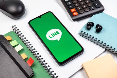 Prag, Çek Cumhuriyeti - 08 18 2025: Merkezinde hat logosu sergilenen bir cep telefonu ile ofis malzemeleri düzenlemesi. Line aramalar, mesajlar ve çokluortam paylaşımı için bir mesajlaşma uygulamasıdır.