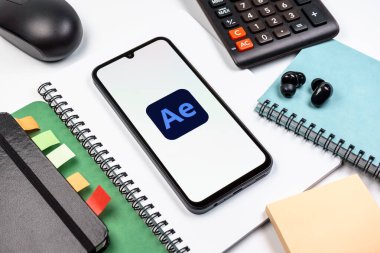 Prag, Çek Cumhuriyeti - 08 18 2025: Ofis malzemelerinin merkezde After Effects logosu sergilenen bir cep telefonu ile düzenlenmesi. After Effects hareket grafikleri ve görsel efektler için bir yazılımdır..