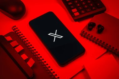 Prag, Çek Cumhuriyeti - 08 18 2025: Merkezinde X logosu sergilenen bir cep telefonu ile ofis malzemeleri düzenlemesi. X, kısa gönderileri ve güncellemeleri paylaşmak için bir platformdur.