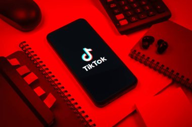 Prag, Çek Cumhuriyeti - 08 18 2025: Merkezde TikTok logosunu gösteren bir cep telefonu ile ofis malzemeleri düzenlemesi. TikTok kısa, yaratıcı ve viral video platformu.