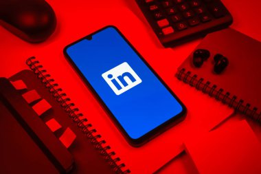 Prag, Çek Cumhuriyeti - 08 18 2025: Merkezde LinkedIn logosunu gösteren bir cep telefonu ile ofis malzemeleri düzenlemesi. LinkedIn, insanları ve şirketleri birbirine bağlayan profesyonel bir ağ..