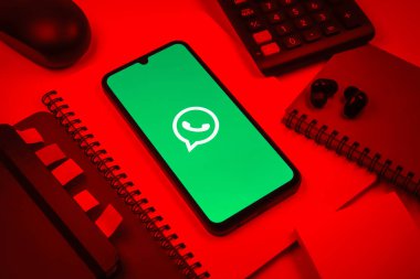 Prag, Çek Cumhuriyeti - 08 18 2025: Ofis malzemelerinin merkezde WhatsApp logosunu gösteren bir cep telefonu ile düzenlenmesi. WhatsApp mesaj, çağrı ve medya göndermek için bir uygulamadır.
