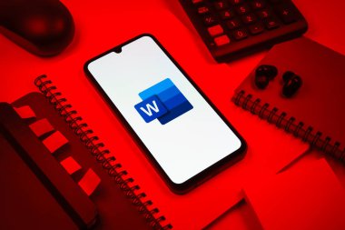 Prag, Çek Cumhuriyeti - 08 18 2025: Merkezinde Word logosu sergilenen bir cep telefonu ile ofis malzemeleri düzenlemesi. Word belge yaratmak ve düzenlemek için bir yazılımdır..
