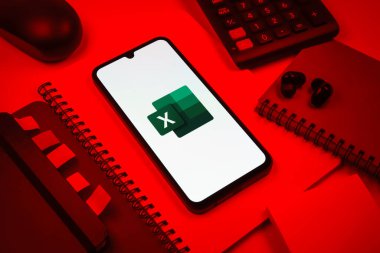 Prag, Çek Cumhuriyeti - 08 18 2025: Excel logosu sergilenen bir cep telefonu ile ofis malzemeleri düzenlemesi. Excel, tablo, veri analizi ve hesaplamalar için bir yazılımdır..
