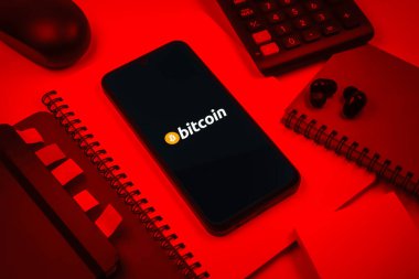 Prag, Çek Cumhuriyeti - 08 18 2025: Merkezde Bitcoin logosu sergilenen bir cep telefonu ile ofis malzemeleri düzenlemesi. Bitcoin merkezi olmayan işlemler için dijital bir kripto para birimidir.