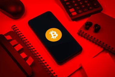 Prag, Çek Cumhuriyeti - 08 18 2025: Merkezde Bitcoin logosu sergilenen bir cep telefonu ile ofis malzemeleri düzenlemesi. Bitcoin merkezi olmayan işlemler için dijital bir kripto para birimidir.